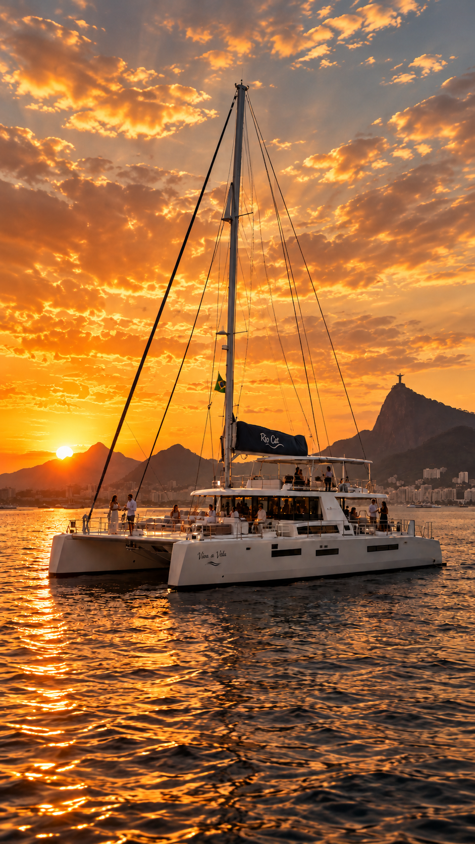 Catamarã de luxo na Baía de Guanabara ao pôr do sol, com convidados a bordo e o Cristo Redentor ao fundo